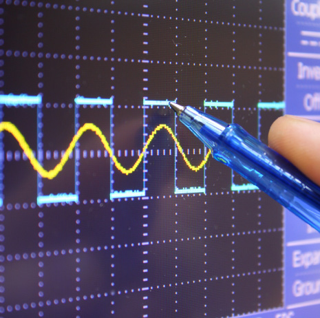 Square wave and sine wave traces on a waveform display being inspected with a stylus